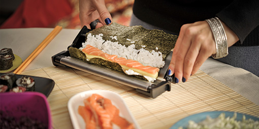 Frau, die Maki mit einer Sushi-Maschine vorbereitet