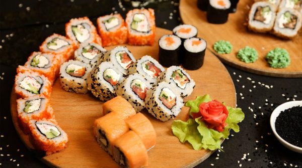 Uma variedade de sushi, com gengibre, wasabi e sementes de gergelim em uma mesa de madeira